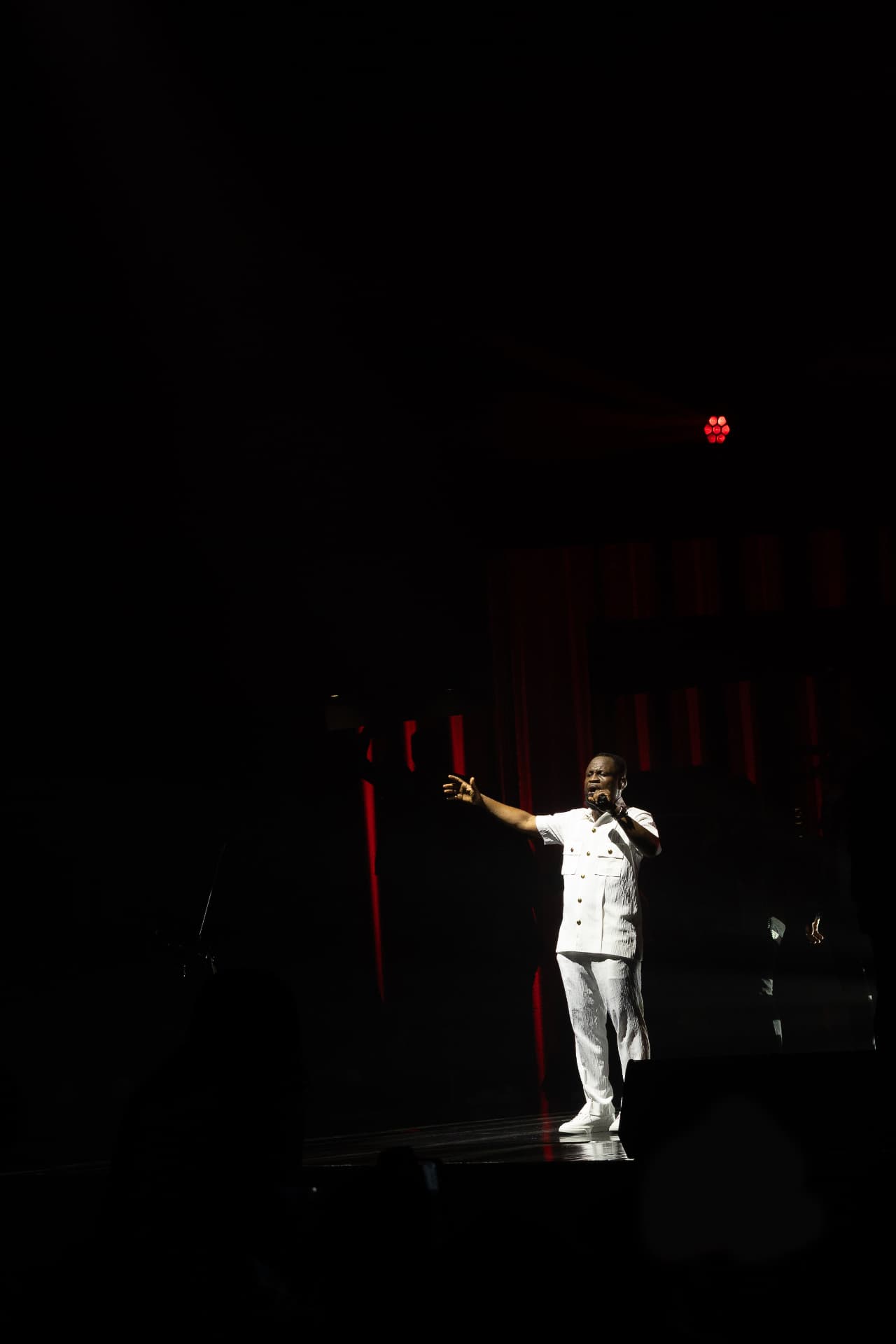 Pastor Edwin Dadson leading worship on a dark stage